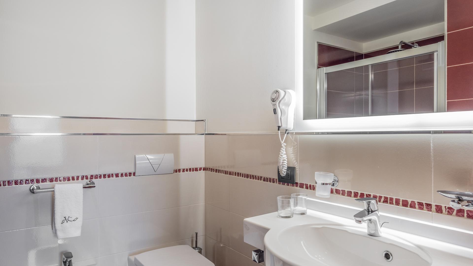 Bagno moderno con specchio illuminato e asciugacapelli.