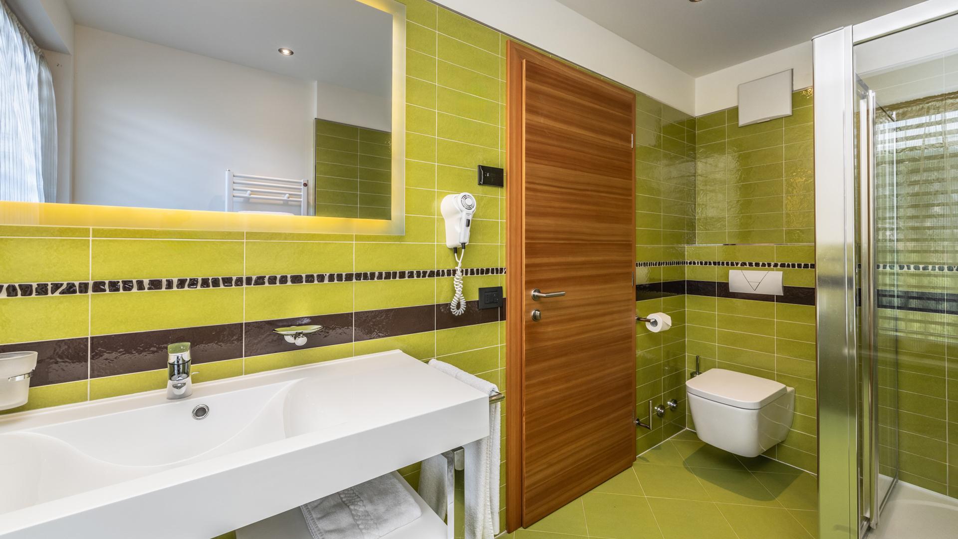 Bagno moderno con piastrelle verdi e doccia.