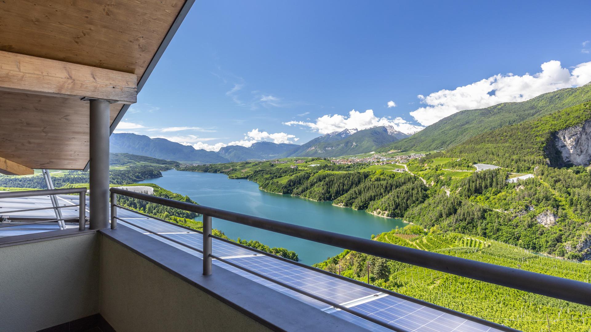 Vista panoramica di un lago e montagne da un balcone.